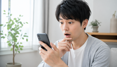 スマホで複数の見積もりを比較し、料金差に驚く日本人の様子を表現したリアルな写真